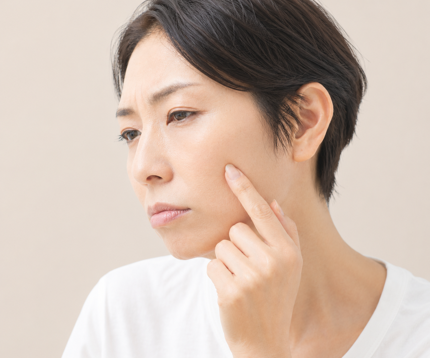 鏡を見て肌の変化を気にする40代の女性